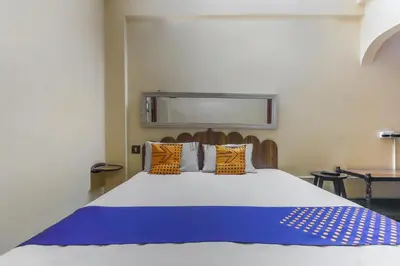 a bedroom with a large bed with orange and blue pillows at SPOT ON Thangam Lodge in Coimbatore