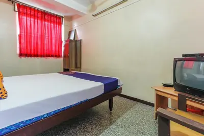 a small bedroom with a bed and a tv at SPOT ON Thangam Lodge in Coimbatore