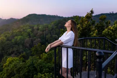 a woman standing on a balcony looking up at the mountains at Coorg Wilderness Resort & Spa in Madikeri