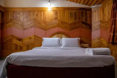 a bedroom with a large bed with wooden walls at JJS Cottages in Coonoor