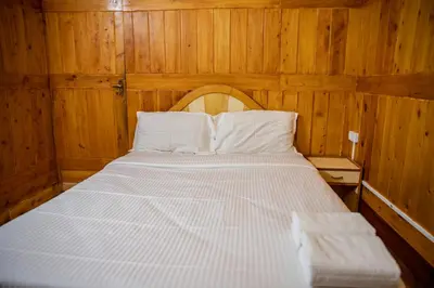 a bed in a room with wooden walls and wooden floors at JJS Cottages in Coonoor
