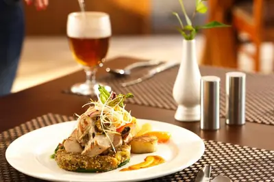 a plate of food on a table with a glass of beer at The Sanihara Hotel & Resort in Vythiri