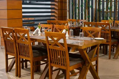 a wooden dining table and chairs in a restaurant at The Sanihara Hotel & Resort in Vythiri