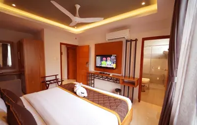 a bedroom with a bed and a tv in a room at WithInn Hotel - Kannur Airport in Kannur