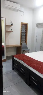 a bedroom with a bed and a desk and a chair at Olive Inn Apartment in Alwaye