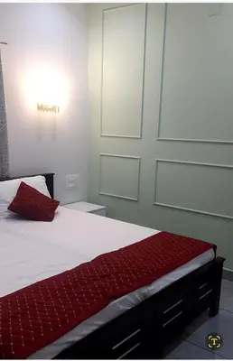 a bedroom with a bed with white sheets and red pillows at Olive Inn Apartment in Alwaye