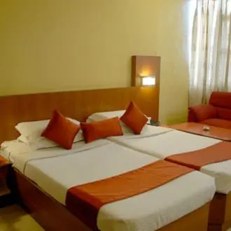 a hotel room with two beds with orange pillows at Hotel Maurya Palace in Mysore