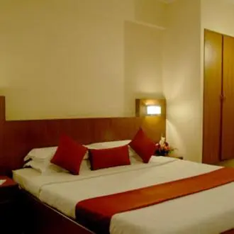 a bedroom with a large bed with red pillows at Hotel Maurya Palace in Mysore