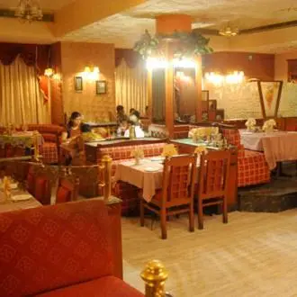 a restaurant with tables and chairs and people in it at Hotel Maurya Palace in Mysore