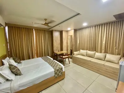 a bedroom with a bed and a couch and a table at KB RESIDENCY in Kozhikode