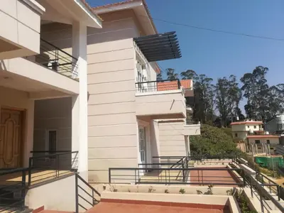 a white house with stairs and a balcony at DEW DROP INN in Ooty