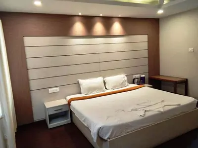 a bedroom with a large bed with a wooden headboard at DEW DROP INN in Ooty
