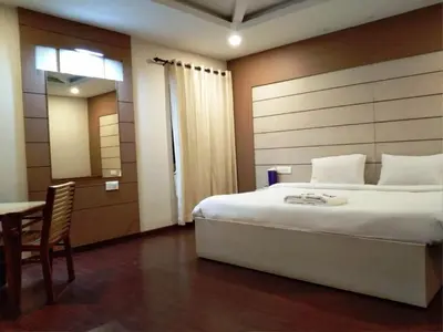 a bedroom with a large bed and a table at DEW DROP INN in Ooty