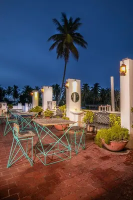 a group of tables and chairs with a palm tree in the background at Aishwarya Residency in Mysore