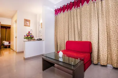 a red chair and a table in a room at Aishwarya Residency in Mysore