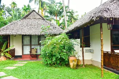 a house with a thatched roof and a yard at Les 3 Elephants in Cherai Beach