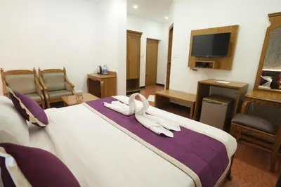a hotel room with a bed with two white towels at Hotel Kairali in Palakkad