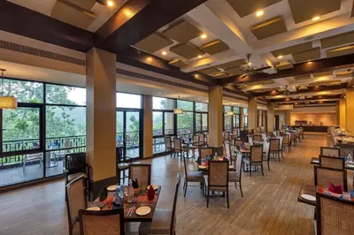 a dining room with tables and chairs and windows at Club Mahindra Virajpet, Coorg in Virajpet