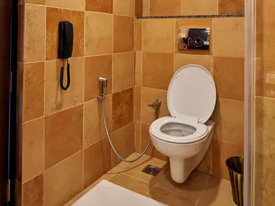 a bathroom with a phone next to a toilet at Club Mahindra Virajpet, Coorg in Virajpet