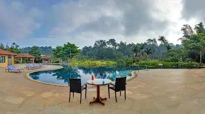 a table and chairs in front of a pool at Club Mahindra Virajpet, Coorg in Virajpet