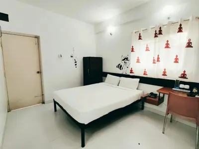 a bedroom with a white bed and a desk at Raccoon Rooms in Mysore