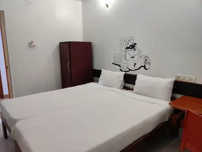 a bedroom with a large white bed and a table at Raccoon Rooms in Mysore
