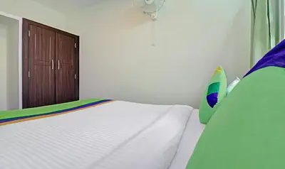 a bedroom with a white bed and a wooden door at Treebo New Redfern, Madikeri in Madikeri