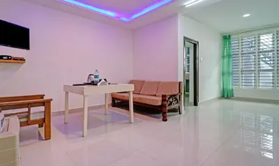 a living room with a couch and a table and a television at Treebo New Redfern, Madikeri in Madikeri