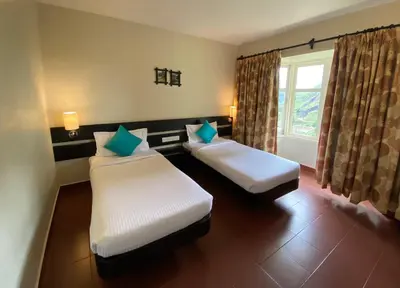a hotel room with two beds and a window at Mountain Retreat - A Hill Country Resort in Ooty