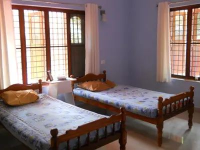 two beds sitting in a room with windows at CoconutCrazy! Homestay in Ottappālam