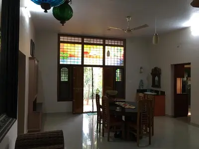 a dining room with a table and chairs and stained glass windows at CoconutCrazy! Homestay in Ottappālam