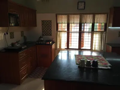 a kitchen with a black counter top and wooden cabinets at CoconutCrazy! Homestay in Ottappālam