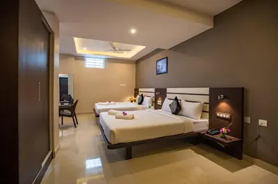 a hotel room with two beds and a desk at Aadya Elite in Mysore