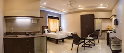 a hotel room with a bed and a kitchen and a living room at Aadya Elite in Mysore