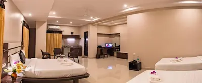 a hotel room with two beds and a living room at Aadya Elite in Mysore