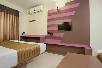 a hotel room with a bed and a tv on a wall at Mannars Residency in Mysore