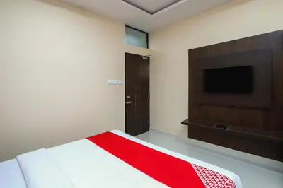 a bedroom with a bed and a flat screen tv at Suvarna Suits in Mysore