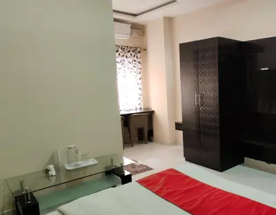 a room with a bed and a sink and a mirror at Suvarna Suits in Mysore