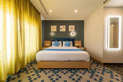 a bedroom with a large bed with yellow curtains at Mintotel Wayanad in Sultan Bathery
