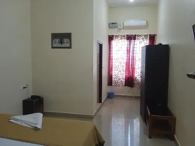 a room with a bed and a window with red curtains at GRAND JP INN Near 2 km from Gundlupet bus stand in Gundlupet