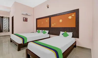 two beds in a room with white walls at GRAND JP INN Near 2 km from Gundlupet bus stand in Gundlupet