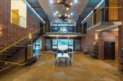 a dining room with a table and chairs in a building at SaffronStays Riverstone 3-BR Riverside Villa with Farm Views in Seringapatam