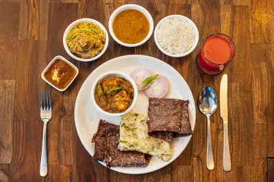 a table with a plate of food and bowls of food at SaffronStays Riverstone 3-BR Riverside Villa with Farm Views in Seringapatam
