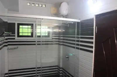 a bathroom with a glass shower with black and white tiles at Jewel Homes Thattekad - ISO 9001 certified Birding & Family Nature Stay in Thattakād