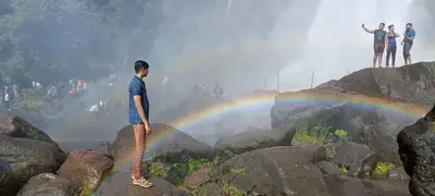 a group of people standing on rocks with a rainbow at Jewel Homes Thattekad - ISO 9001 certified Birding & Family Nature Stay in Thattakād
