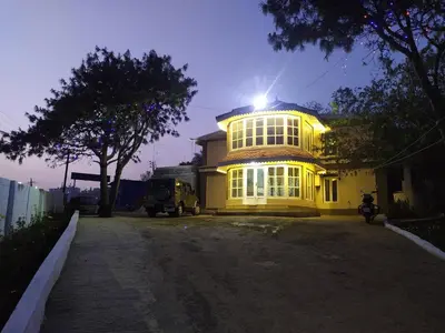 a large yellow building with the light shining on it at Heritage Holiday Home in Ooty