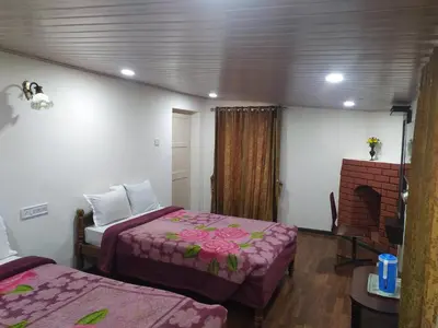 a hotel room with two beds and a fireplace at Heritage Holiday Home in Ooty