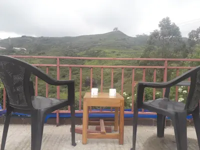 two chairs and a table with two mugs on it at Munnar Brindavan Cottage in Munnar
