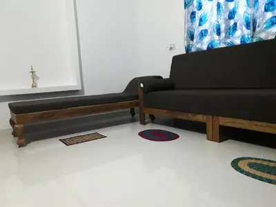 a living room with a black couch and a cross on the wall at Munnar Brindavan Cottage in Munnar