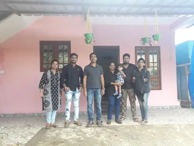 a group of people standing in front of a pink house at Munnar Brindavan Cottage in Munnar